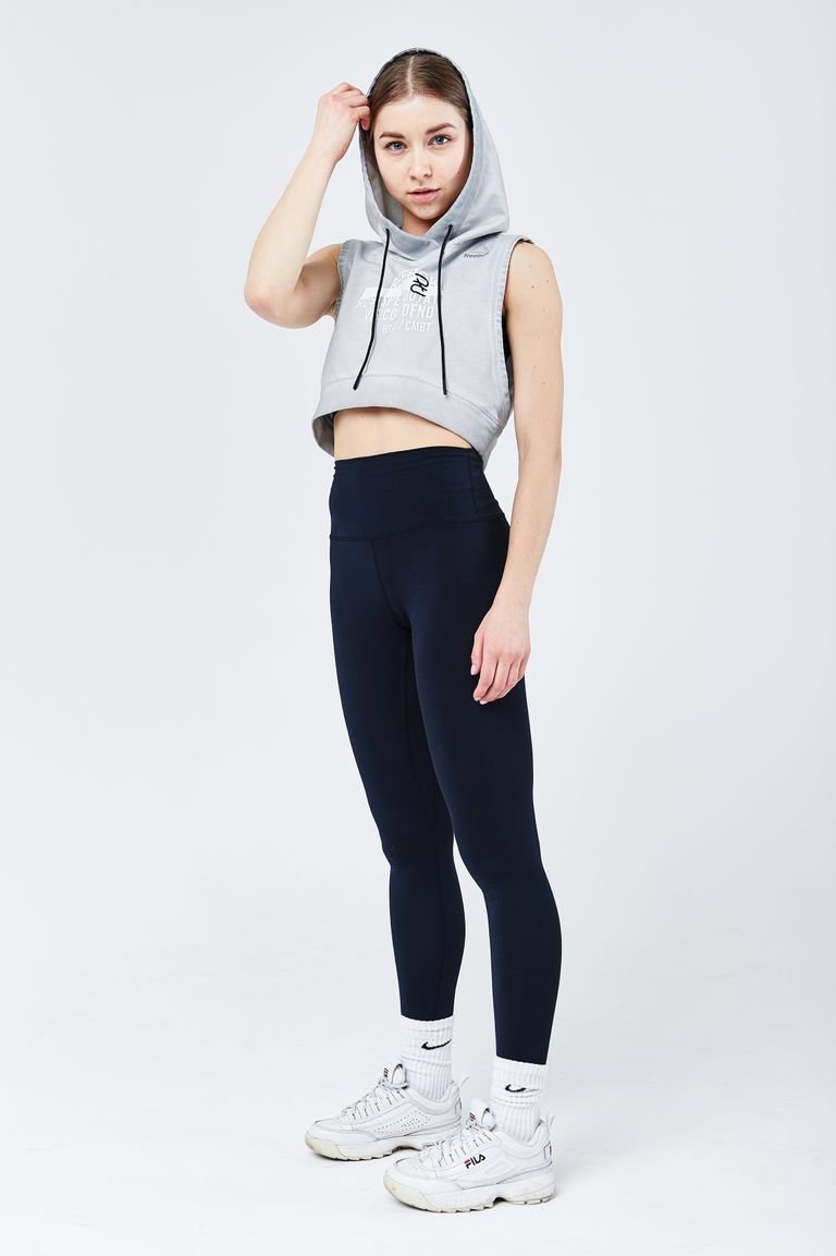 Full-body studio shot of a young woman in fashionable workout clothes on a white background.